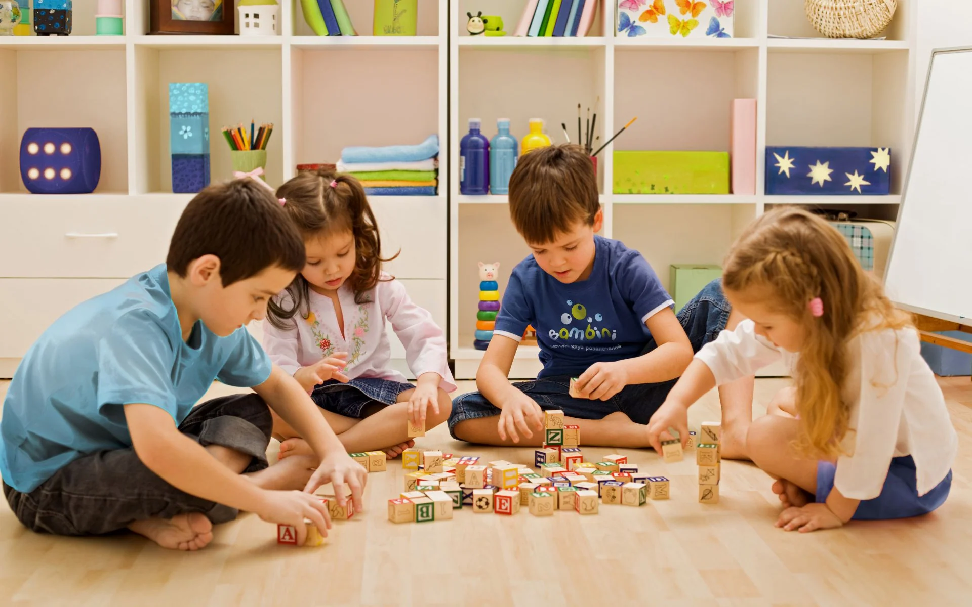Дети играют в кубики, на мальчике футболка Bambini