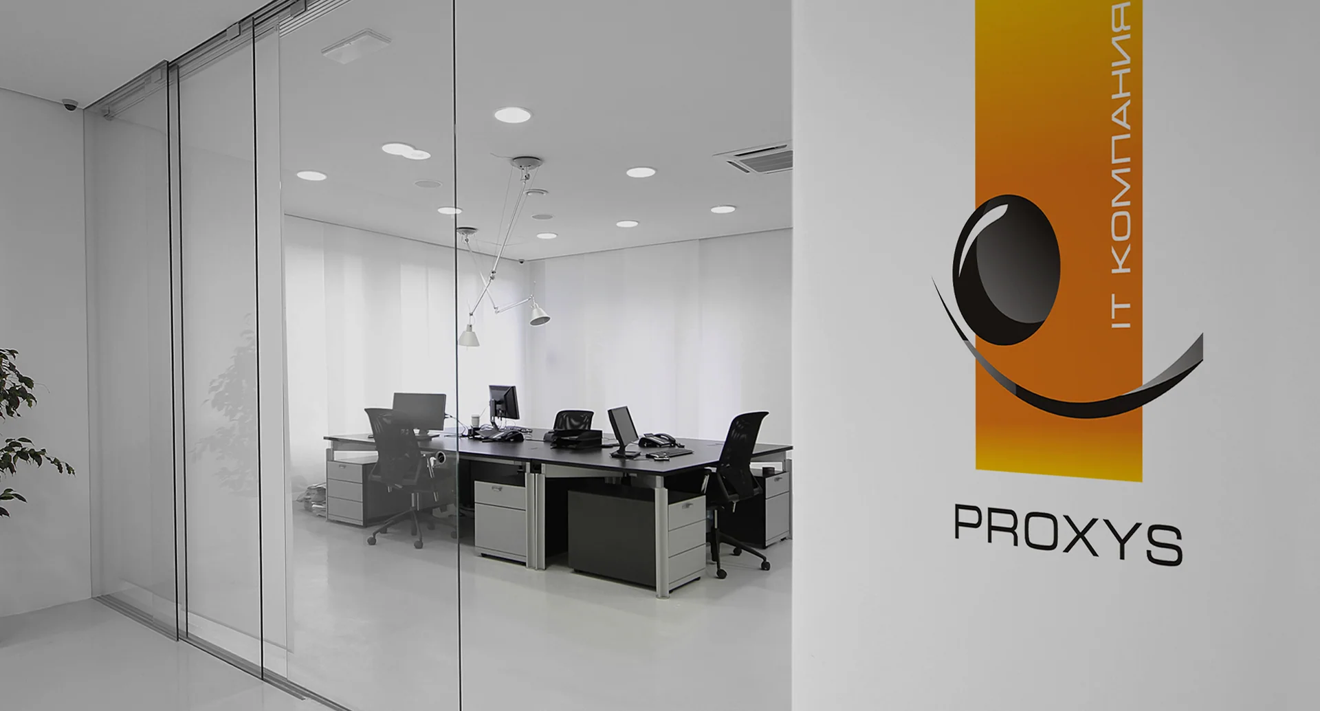 Офис Proxys со стеклянной перегородкой и вертикальным логотипом на стене