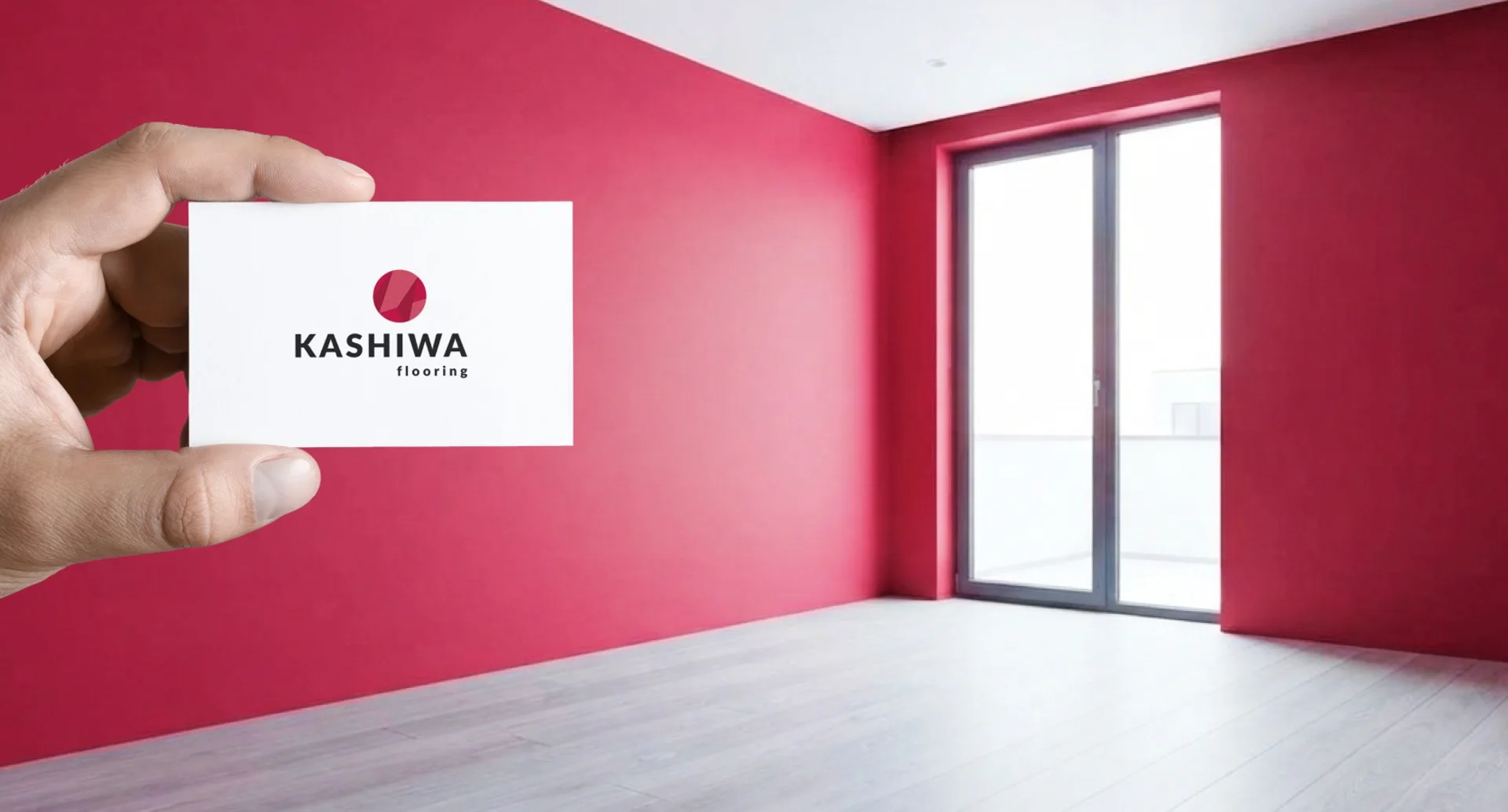Визитка Kashiwa Flooring в руке на фоне комнаты с красной стеной и новым полом